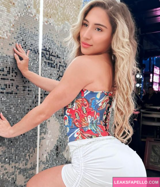 Abella Danger wearing flowery blouse taking an outdoor pic against a wall