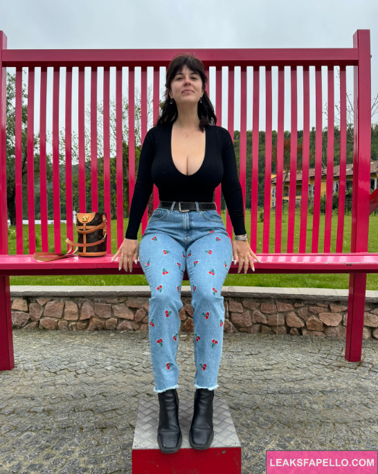 Mady Gio sitting in park bench wearing sexy pants and a black top