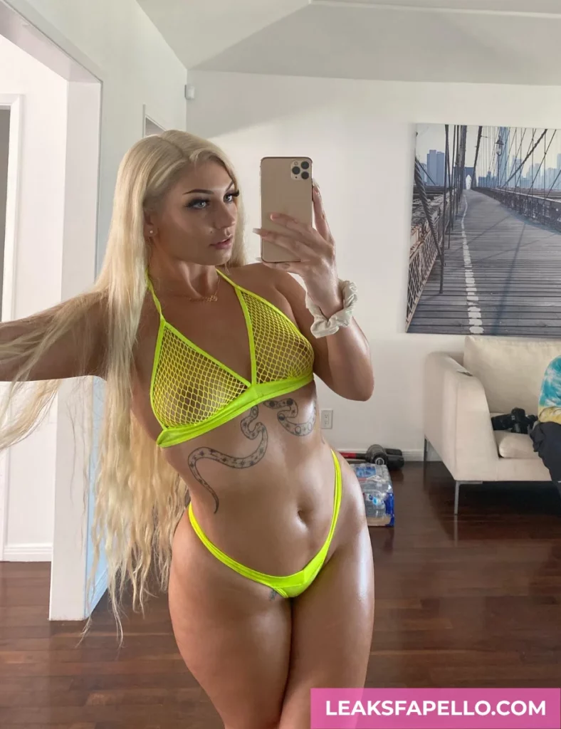 Vivian Taylor, busty MILF tattooed OnlyFans model, wearing a neon green 2 piece net style bikini, having a mirror shot selfie