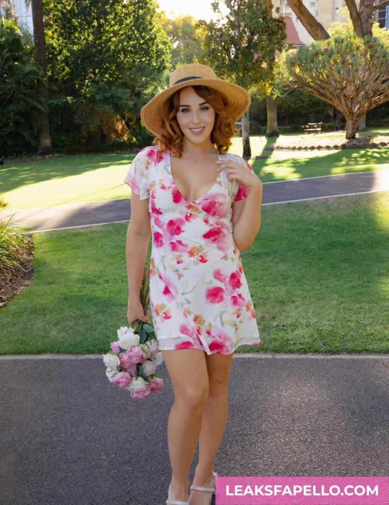 Nova Hawthorne, curvy brunette big tits OnlyFans model, wearing a white dress with floral design, holding bouquet of roses
