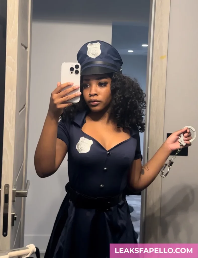 Angel Ace Pierce, ebony tattooed OnlyFans model, wearing a sexy police outfit, holding a handcuff