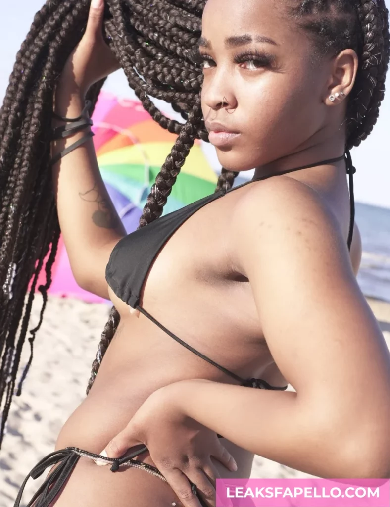 Angel Ace Pierce, ebony tattooed OnlyFans model, wearing a sexy black swimsuit, flexing her braided hair