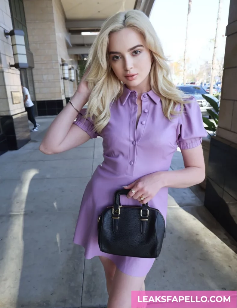 Lexi Lore, Blonde Bid Tits Pierced and Tattooed OnlyFans model, wearing a purple dress and carrying a small black bag