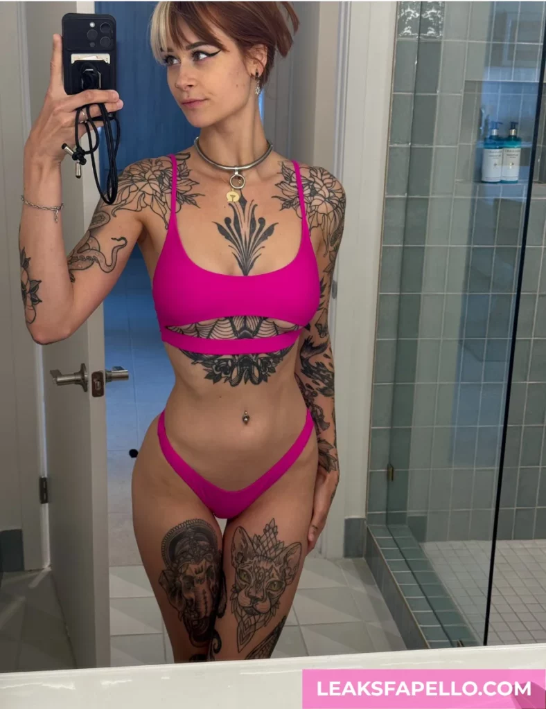 SallyDinosaur, a tattooed curvy OnlyFans model, wearing a pink lingerie, mirror selfie inside the bathroom