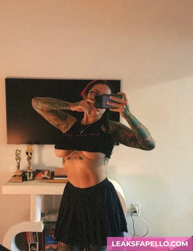 Bianca Bailee, thick curvy tattooed OnlyFans model, wearing black top and skirt, showing the lower portion of her tits
