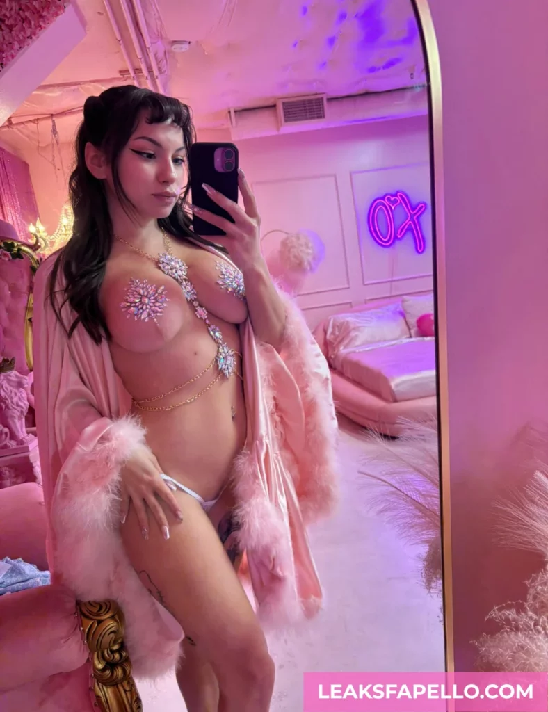 Dakota Quinn, Tattooed Busty Curvy OnlyFans model, is wearing a beaded nipple cover while wearing a pink robe