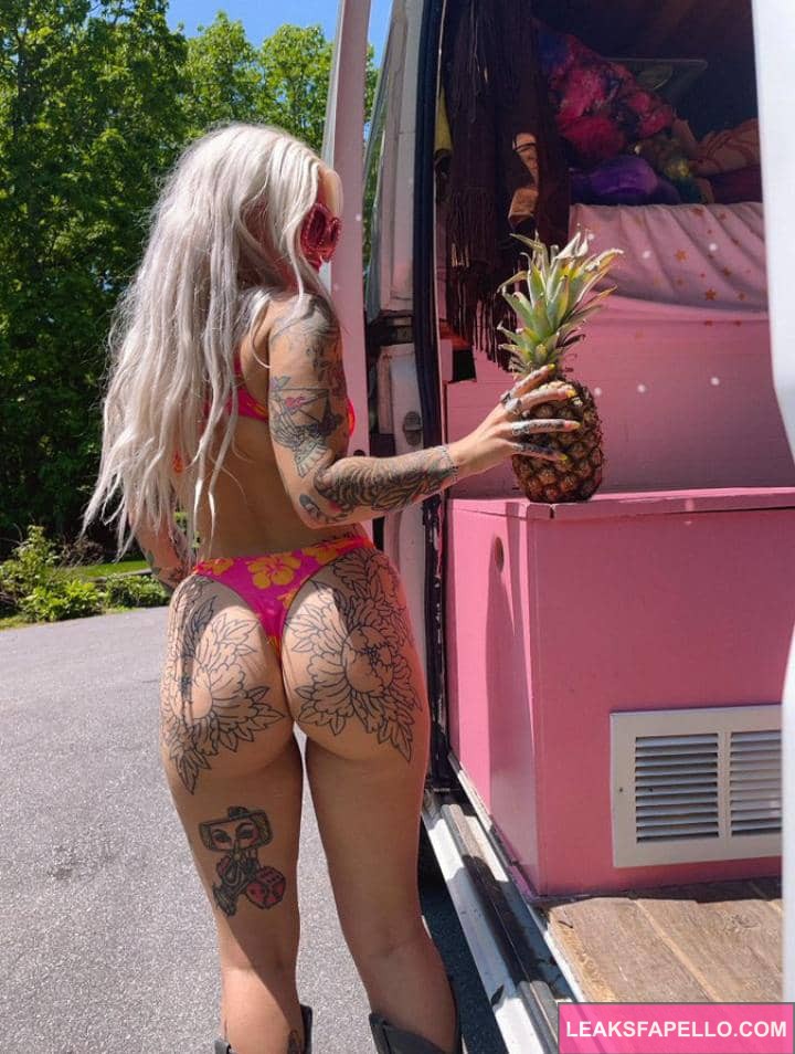 Emily Sedona standing beside her van wearing a pink bikini holding a pineapple