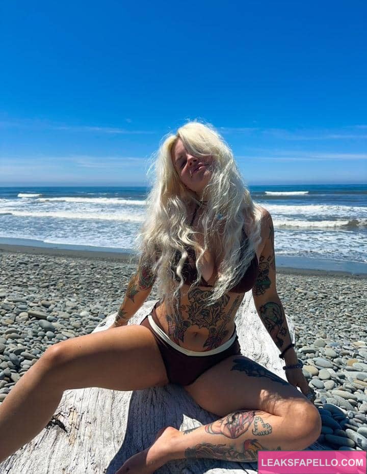 Emily Sedona sitting on the shoreline wearing a bikini